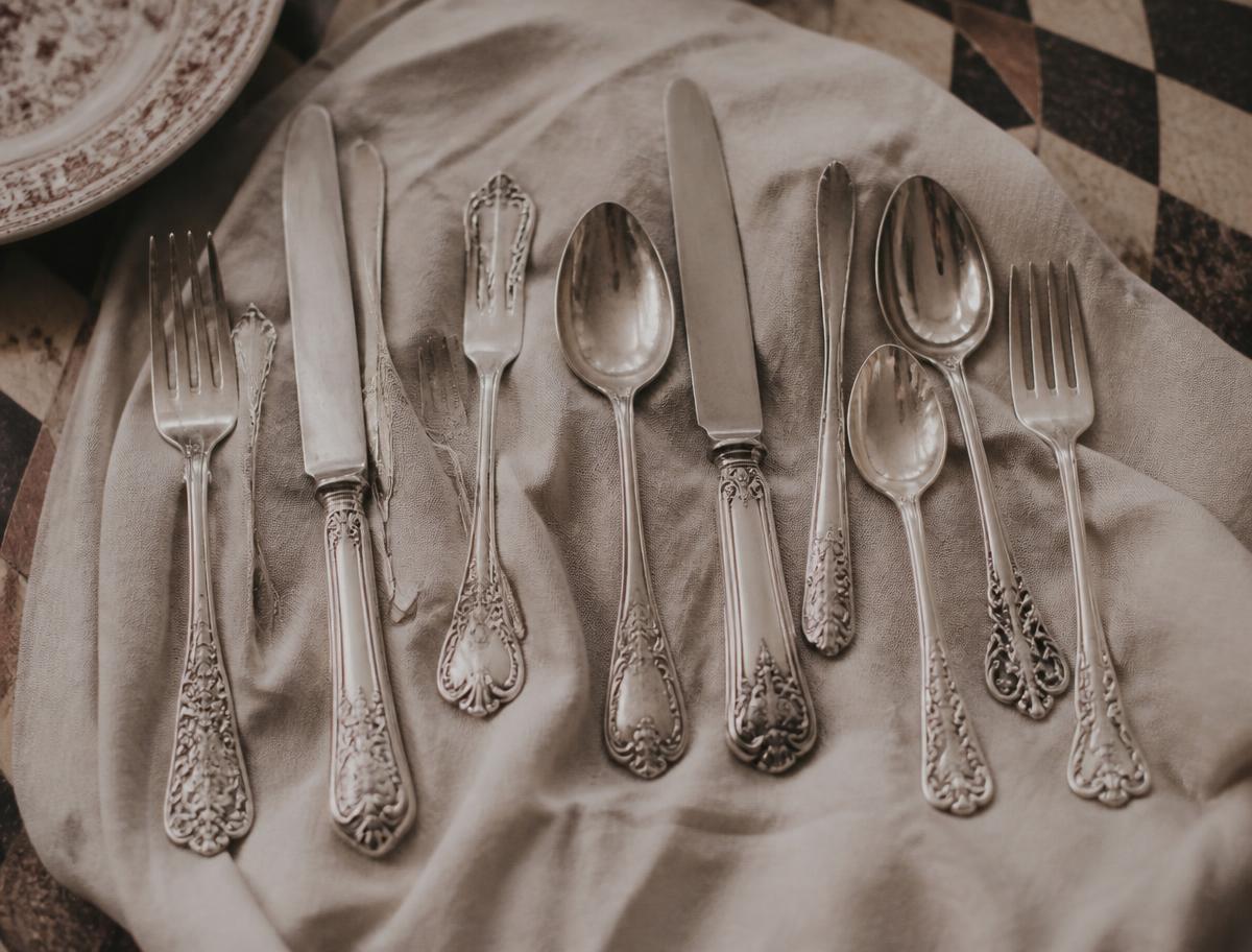 Three different antique silver plate patterns arranged together on linen
