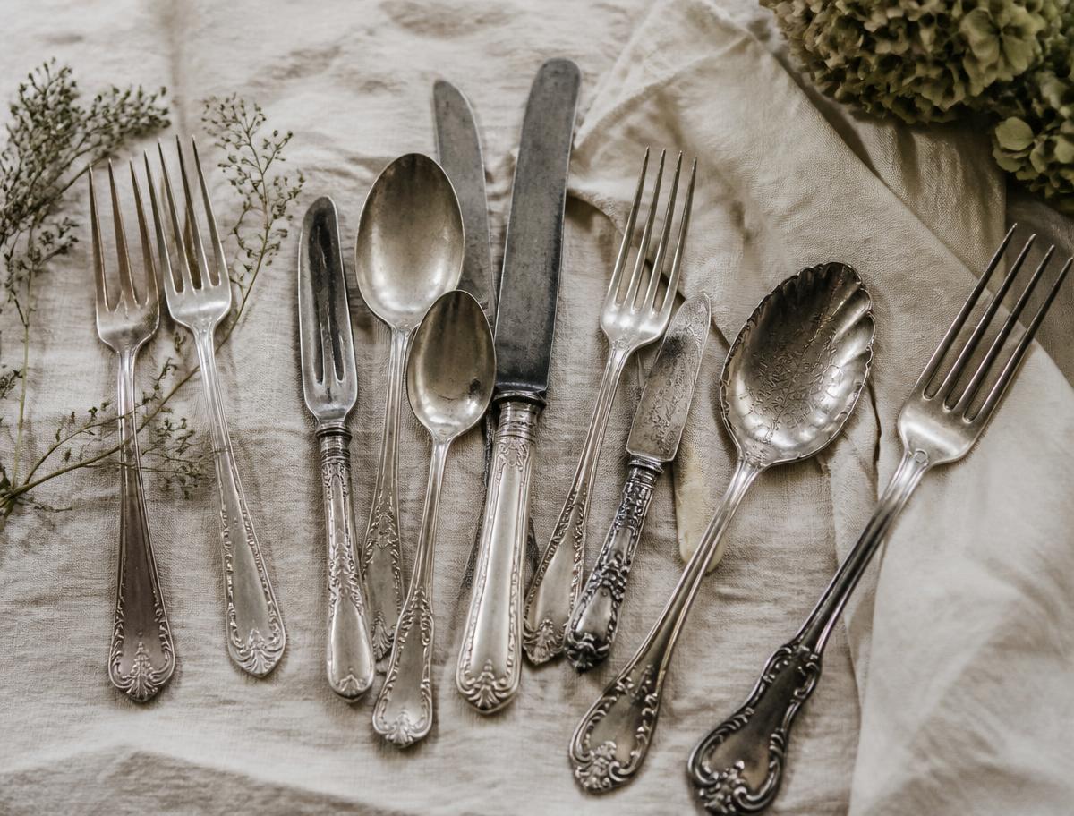 Antique silver plate cutlery in varied patterns laid on cream linen